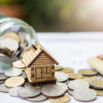 maison miniature posée sur des pièces de monnaie
